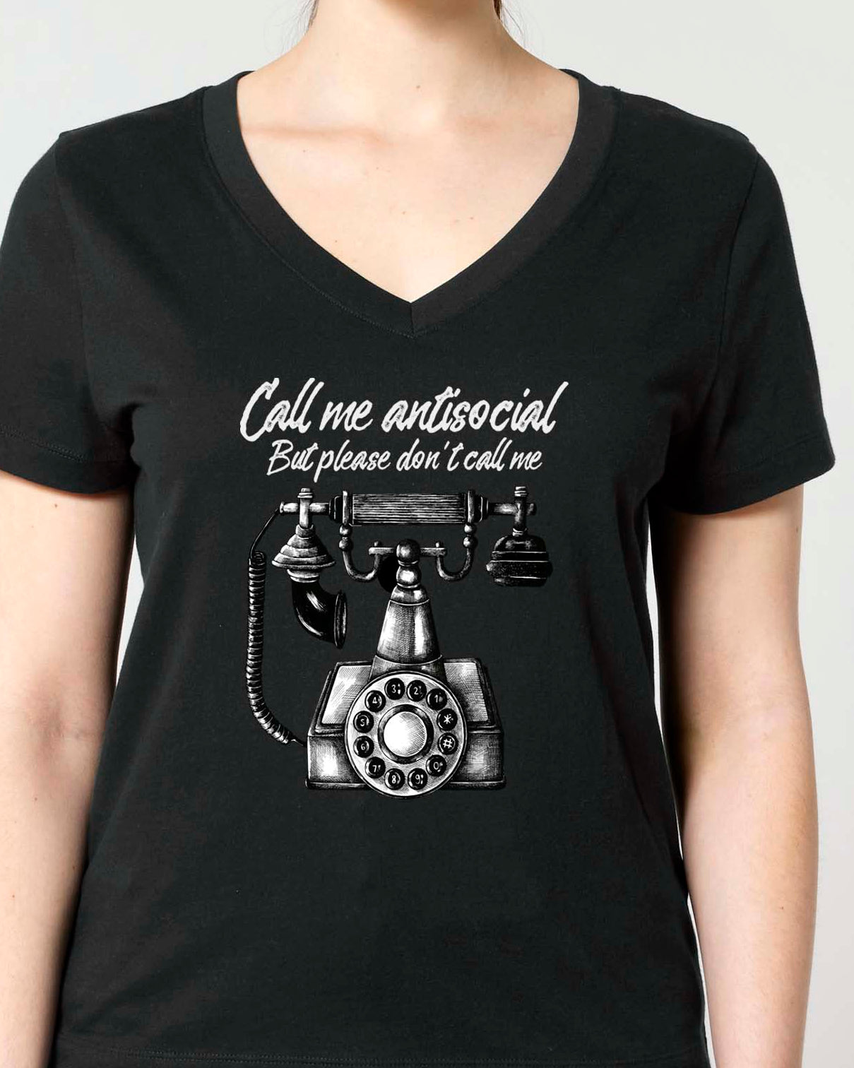A woman modeling a black V-neck t-shirt with a Vintage graphic print of a rotary phone and the text 'Call me antisocial but please don't call me'.