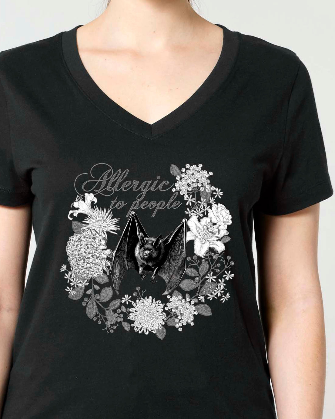 A woman modeling a black V-neck t-shirt with a Vintage style monochrome graphic print of a bat and flowers.