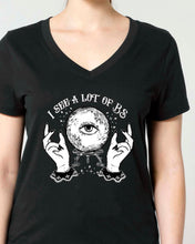 A woman modeling a black V-neck t-shirt with a white graphic print of a crystal ball, hands, and the text 'I SEE A LOT OF BS'. 