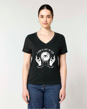 A woman modeling a black V-neck t-shirt with a white graphic print of a crystal ball, hands, and the text 'I SEE A LOT OF BS'. 