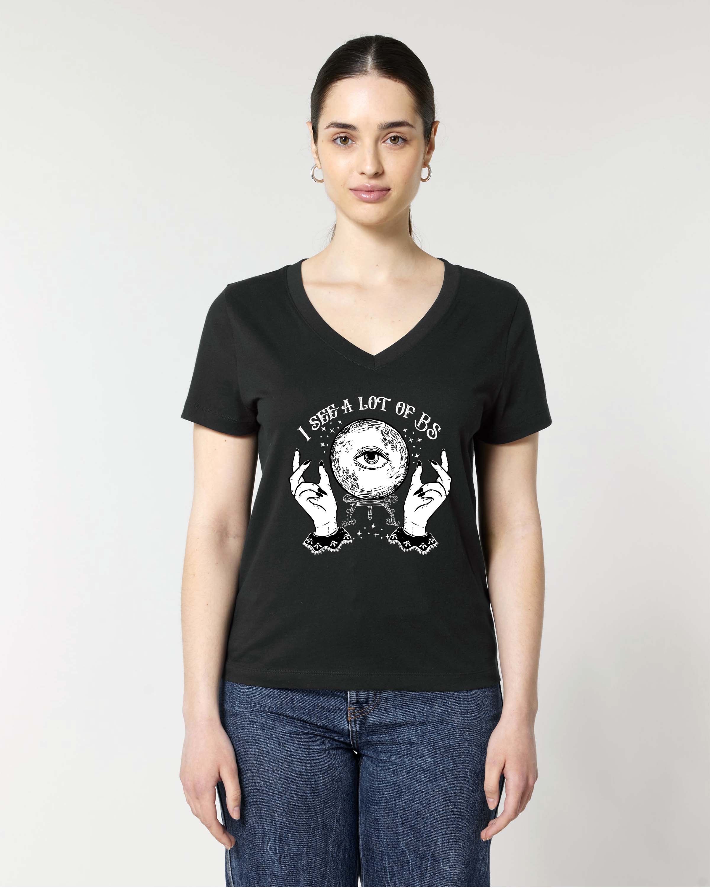 A woman modeling a black V-neck t-shirt with a white graphic print of a crystal ball, hands, and the text 'I SEE A LOT OF BS'. 