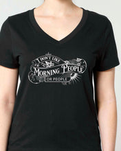 A woman modeling a black v-neck t-shirt with a white graphic print that reads 'I DON'T LIKE MORNING PEOPLE ANY MORE' in a Gothic Victorian vintage-style font.