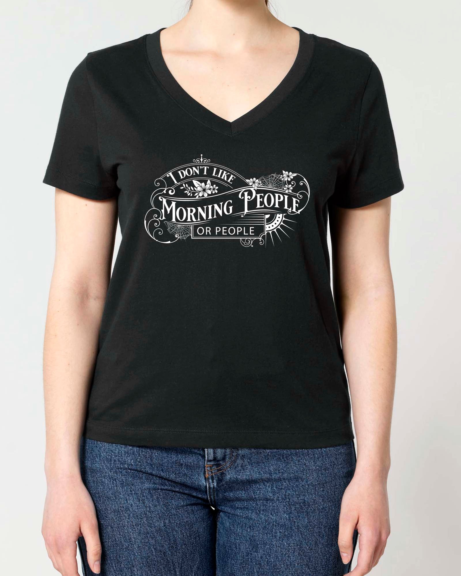 A woman modeling a black v-neck t-shirt with a white graphic print that reads 'I DON'T LIKE MORNING PEOPLE ANY MORE' in a Gothic Victorian vintage-style font. 