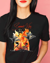 A woman wearing a black graphic t-shirt with a 'Summer Vibes' skeleton posed against a flame background.
