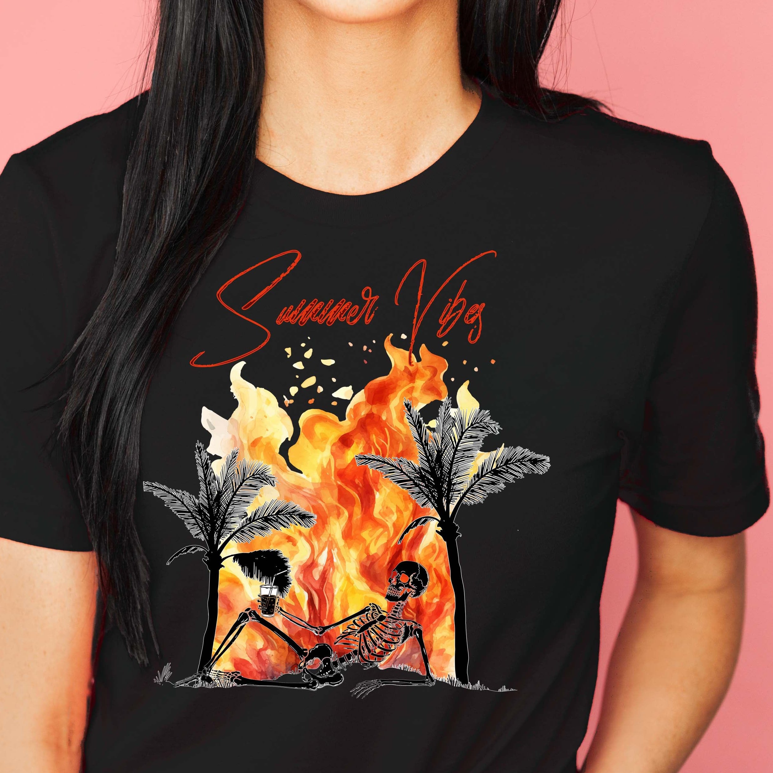 A woman wearing a black graphic t-shirt with a 'Summer Vibes' skeleton posed against a flame background.